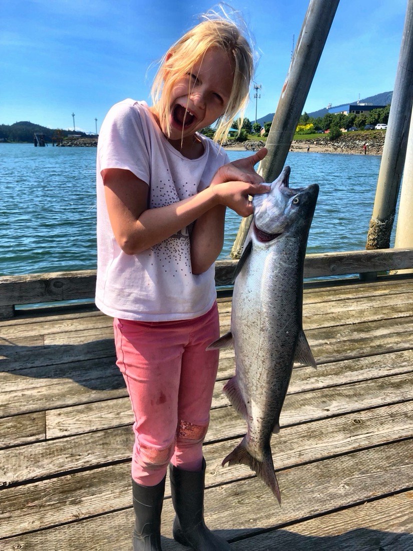 Courtney Skinner holding a coho salmon on the dock in Juneau