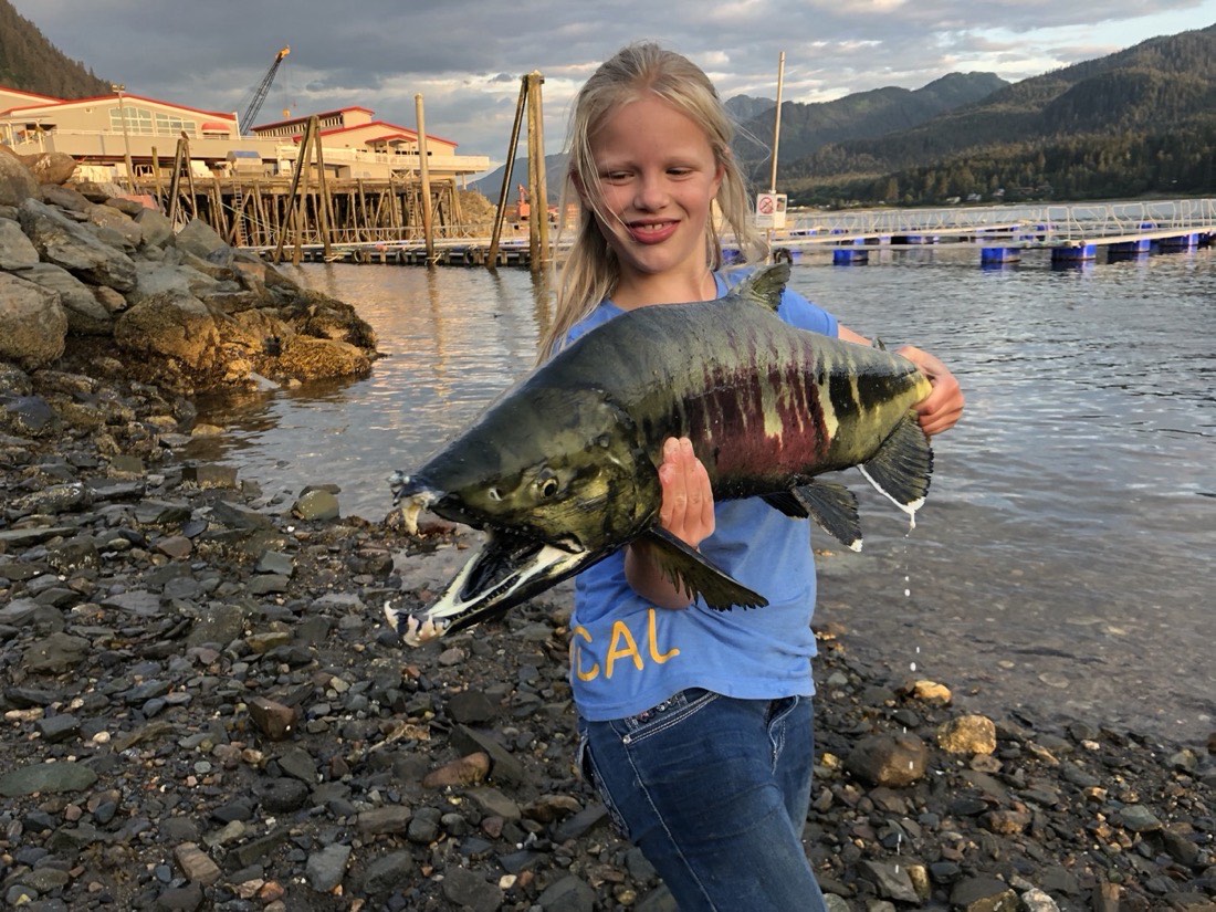 Courtney Skinner holding a salmon at dusk in Juneau, Alaska